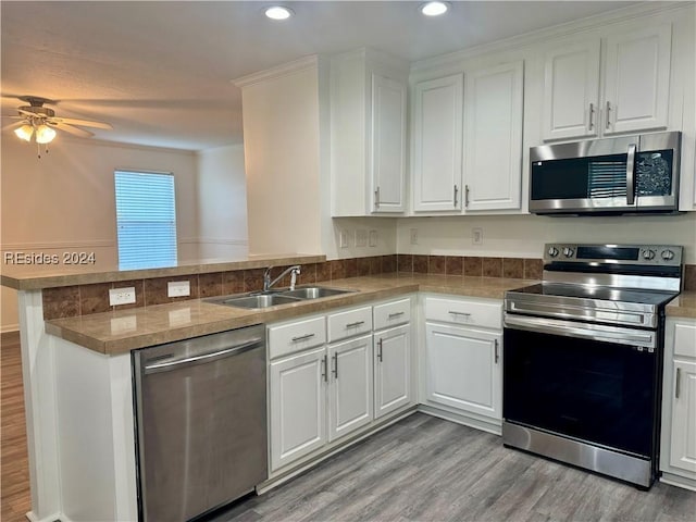 kitchen with sink, white cabinets, light hardwood / wood-style floors, kitchen peninsula, and stainless steel appliances