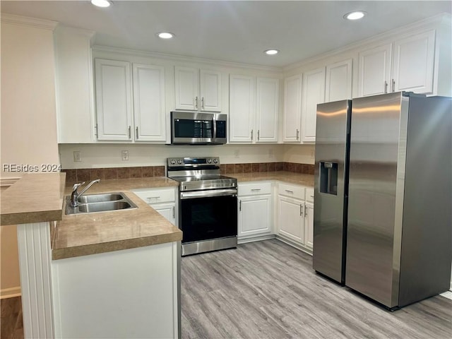 kitchen with sink, light hardwood / wood-style flooring, white cabinetry, stainless steel appliances, and kitchen peninsula