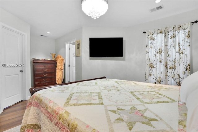 bedroom with wood-type flooring and a notable chandelier