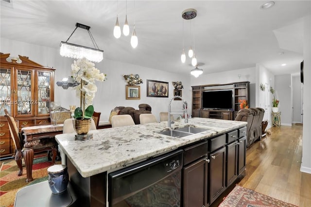 kitchen with sink, light hardwood / wood-style flooring, black dishwasher, an island with sink, and decorative light fixtures