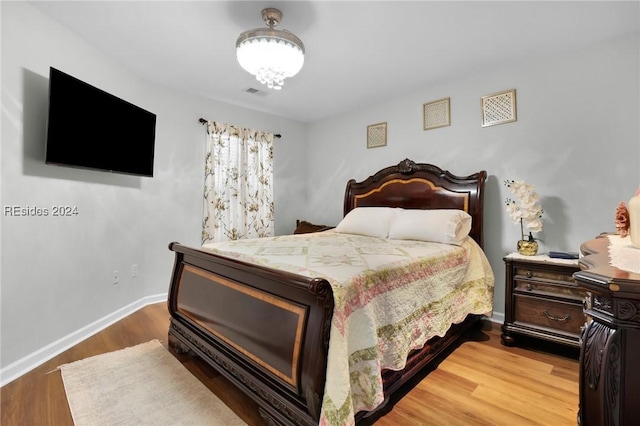 bedroom with wood-type flooring and an inviting chandelier