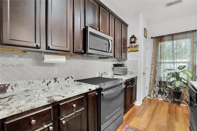 kitchen featuring dark brown cabinetry, light hardwood / wood-style flooring, tasteful backsplash, and appliances with stainless steel finishes