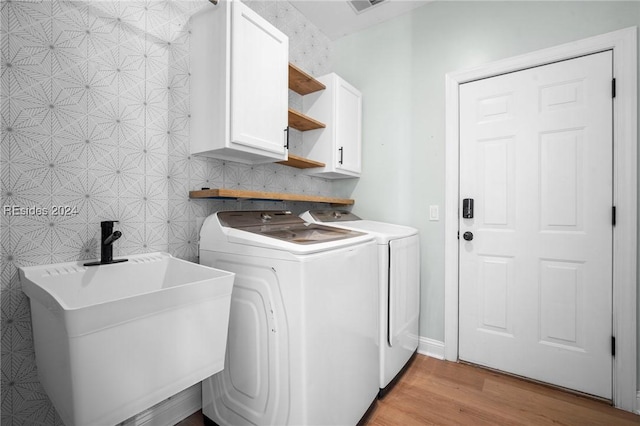 clothes washing area with sink, light hardwood / wood-style flooring, cabinets, and independent washer and dryer