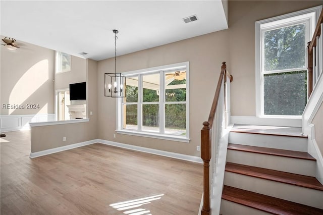 staircase featuring hardwood / wood-style flooring, a healthy amount of sunlight, and a notable chandelier