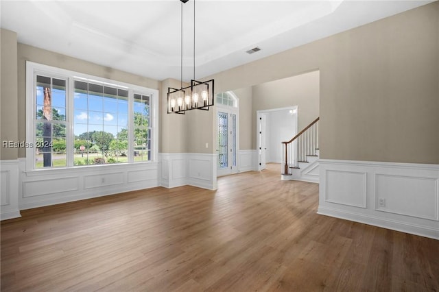 unfurnished dining area featuring light hardwood / wood-style flooring and a raised ceiling