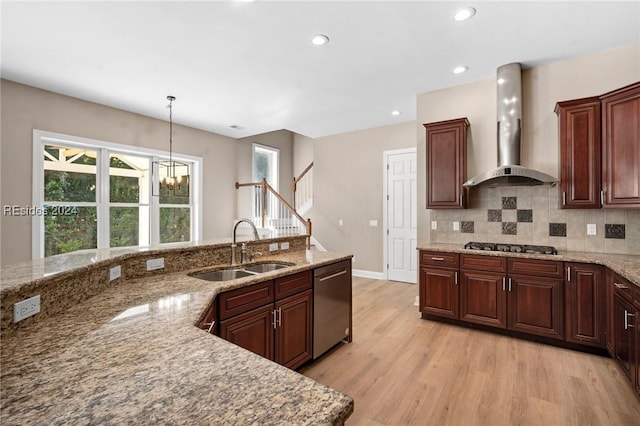 kitchen with sink, light stone counters, appliances with stainless steel finishes, light hardwood / wood-style floors, and wall chimney range hood