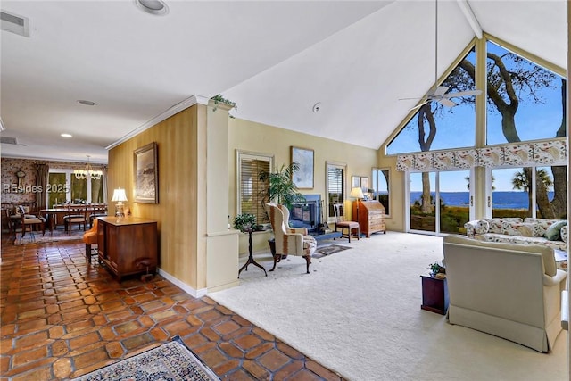 living room with vaulted ceiling, ceiling fan with notable chandelier, wooden walls, dark colored carpet, and ornamental molding