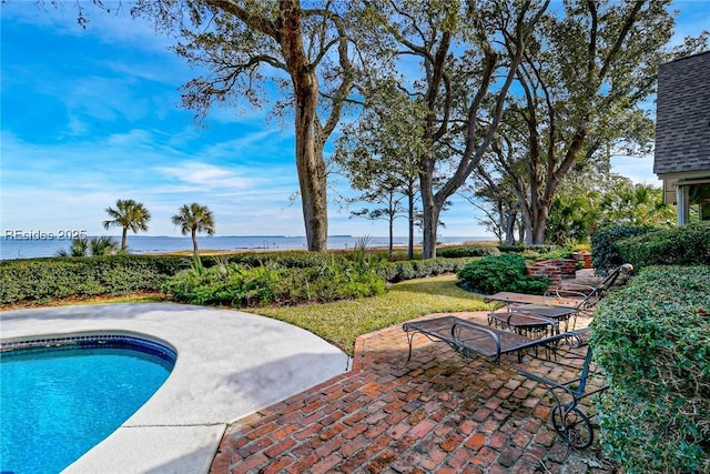 view of pool with a water view and a patio area