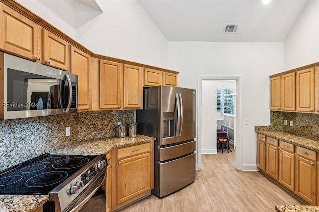 kitchen featuring tasteful backsplash, appliances with stainless steel finishes, light stone counters, and light hardwood / wood-style floors