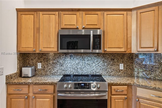 kitchen with appliances with stainless steel finishes, dark stone counters, and decorative backsplash