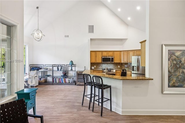 kitchen with appliances with stainless steel finishes, hanging light fixtures, backsplash, high vaulted ceiling, and stone countertops