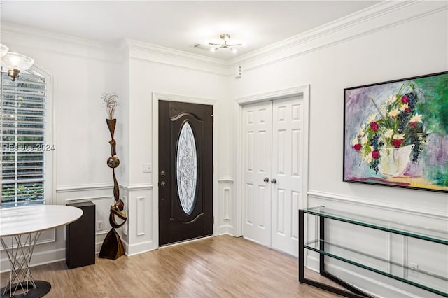 foyer with ornamental molding and light wood-type flooring