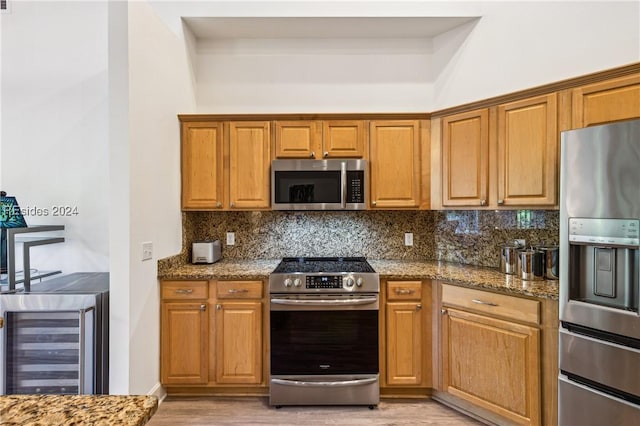 kitchen featuring backsplash, stainless steel appliances, wine cooler, light hardwood / wood-style floors, and stone countertops