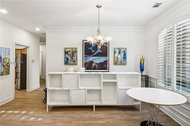 dining room featuring an inviting chandelier, ornamental molding, and light hardwood / wood-style floors