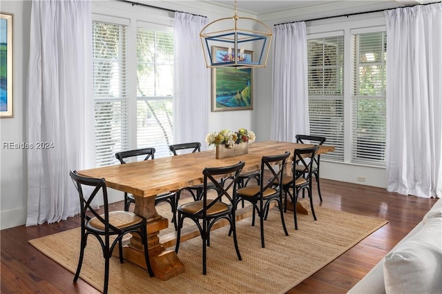 dining area featuring dark wood-type flooring, a healthy amount of sunlight, crown molding, and an inviting chandelier