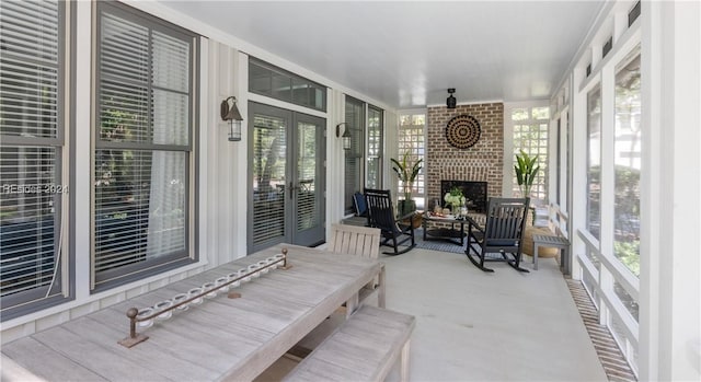 sunroom featuring a brick fireplace and french doors