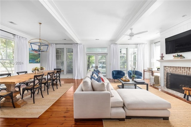 living room with crown molding, a brick fireplace, hardwood / wood-style floors, and ceiling fan