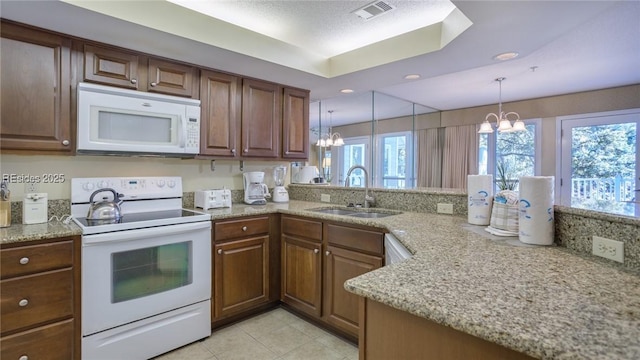 kitchen featuring sink, hanging light fixtures, white appliances, kitchen peninsula, and an inviting chandelier