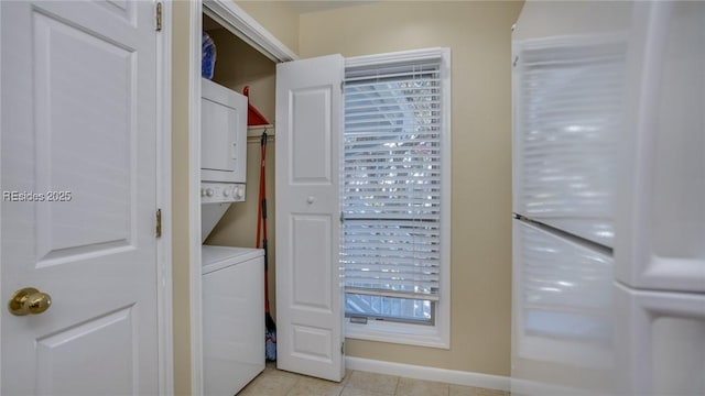 washroom with light tile patterned flooring, stacked washer / drying machine, and a wealth of natural light