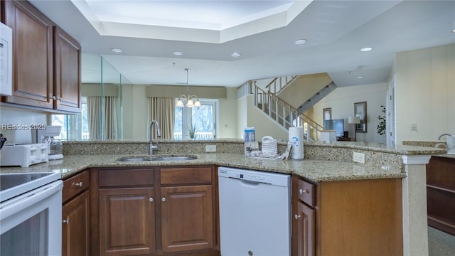 kitchen with pendant lighting, sink, a chandelier, kitchen peninsula, and white appliances