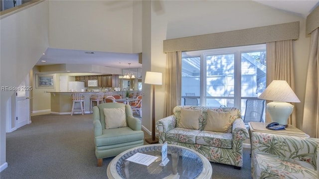 carpeted living room featuring a towering ceiling and a chandelier