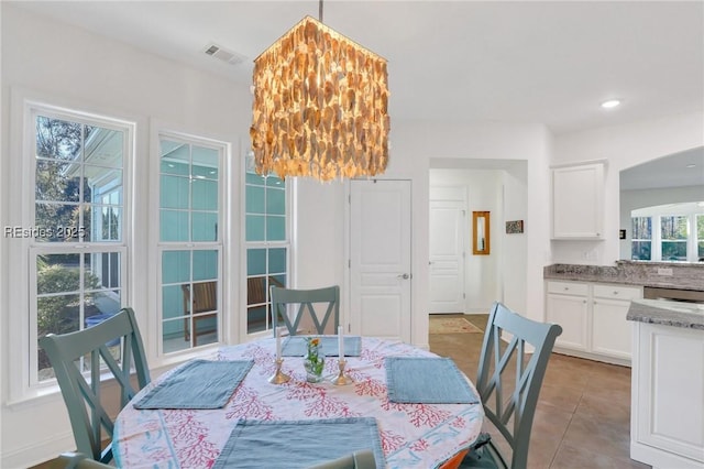 tiled dining room featuring an inviting chandelier and a wealth of natural light