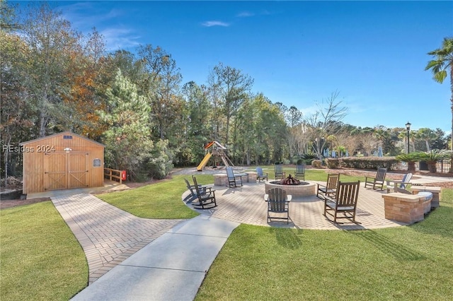 view of yard with a shed, a fire pit, a patio, and a playground