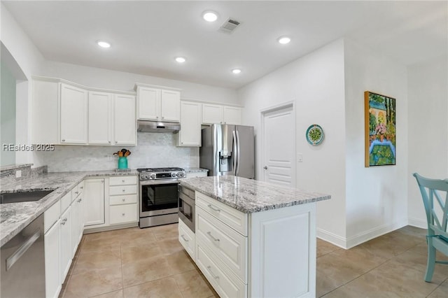 kitchen featuring white cabinetry, light stone counters, stainless steel appliances, and a kitchen island