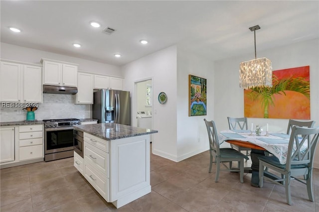 kitchen featuring white cabinetry, stainless steel appliances, washer / dryer, and pendant lighting