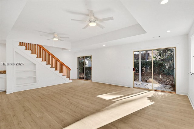 unfurnished living room with light hardwood / wood-style flooring, ceiling fan, and built in shelves