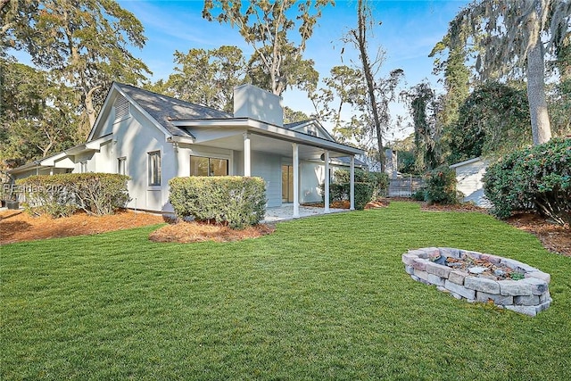 view of side of home with a yard, a fire pit, and a patio area