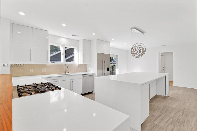 kitchen with white cabinetry, sink, stainless steel appliances, and a center island