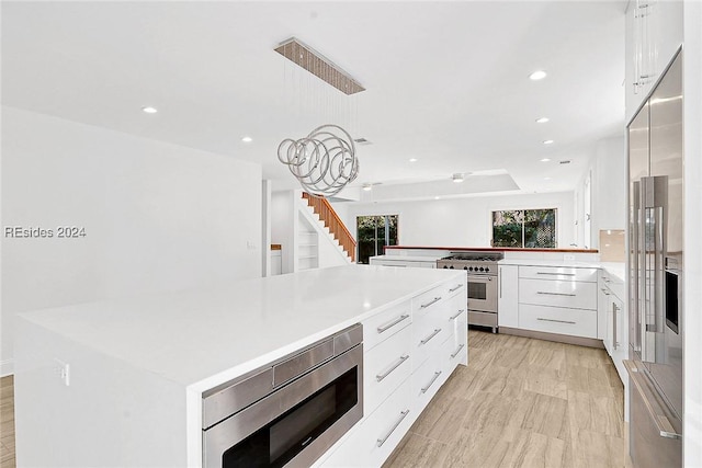 kitchen with stainless steel appliances, white cabinetry, a large island, and kitchen peninsula