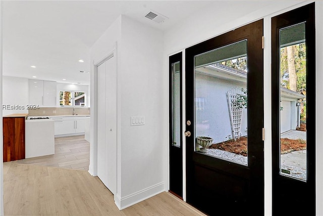 entrance foyer with a healthy amount of sunlight, sink, and light wood-type flooring