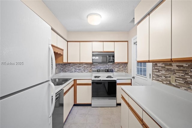 kitchen featuring light tile patterned flooring, white cabinets, decorative backsplash, and black appliances