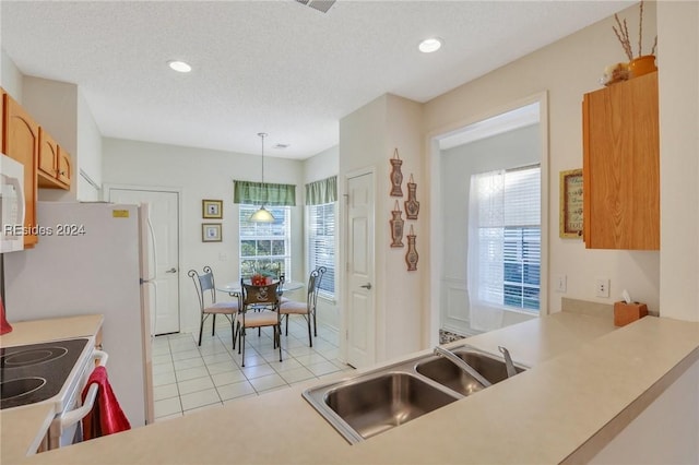 kitchen featuring a healthy amount of sunlight, decorative light fixtures, sink, and light tile patterned floors