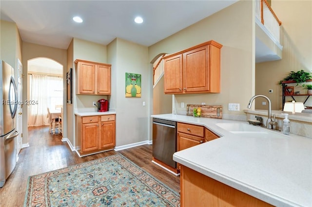 kitchen featuring appliances with stainless steel finishes, sink, dark wood-type flooring, and kitchen peninsula