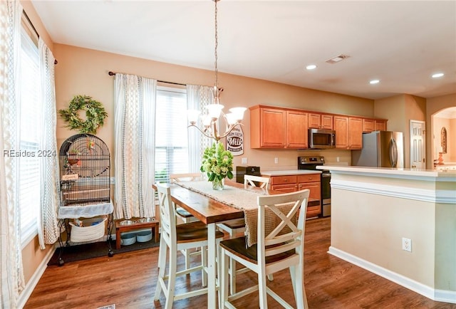 kitchen featuring a breakfast bar, an inviting chandelier, wood-type flooring, decorative light fixtures, and appliances with stainless steel finishes