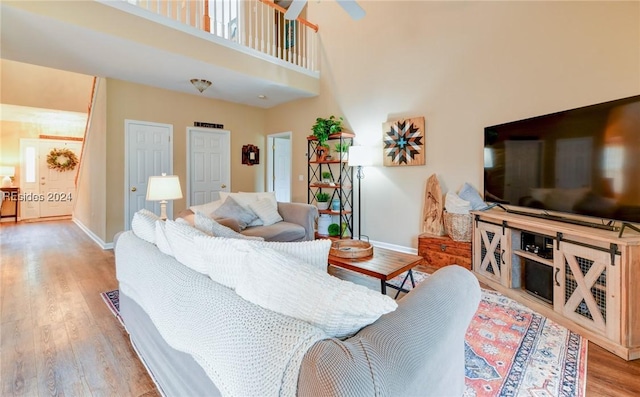 living room with a towering ceiling and light wood-type flooring