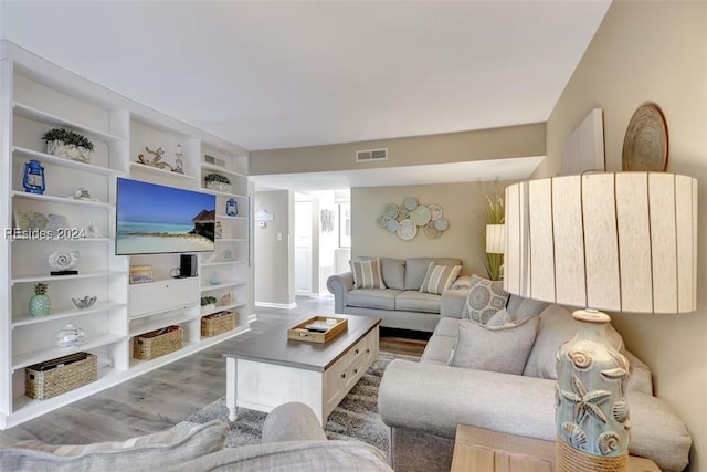 living room featuring built in features and light hardwood / wood-style flooring