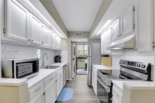 kitchen with sink, decorative backsplash, white cabinets, and appliances with stainless steel finishes