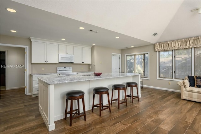 kitchen featuring white cabinetry, sink, light stone countertops, a center island with sink, and white appliances