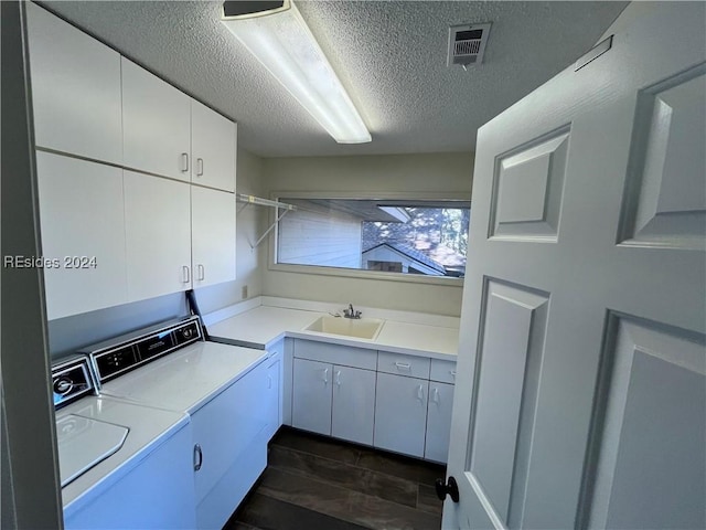 washroom with washer and dryer, sink, cabinets, and a textured ceiling