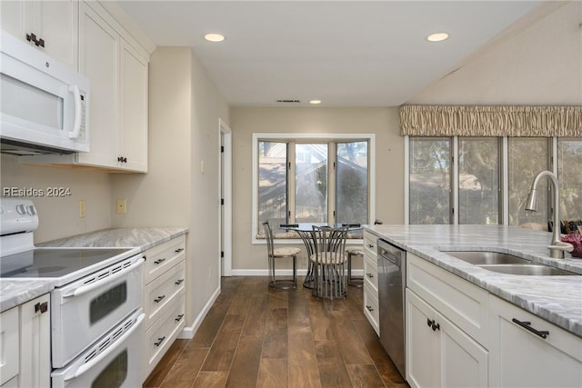 kitchen with sink, light stone counters, white cabinets, and white appliances