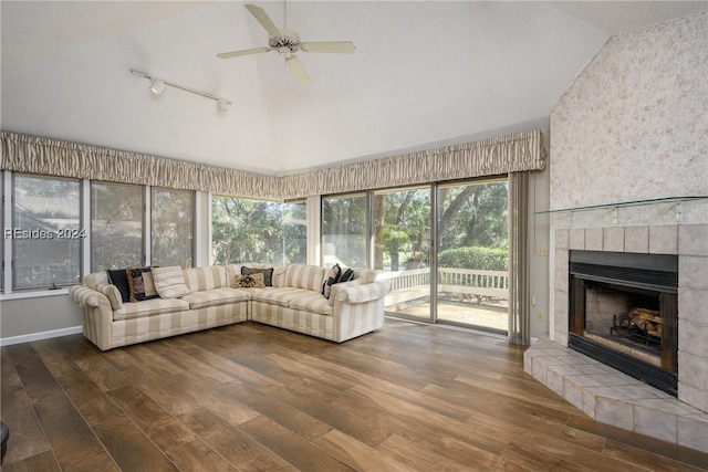 unfurnished living room with a tiled fireplace, dark wood-type flooring, high vaulted ceiling, and ceiling fan