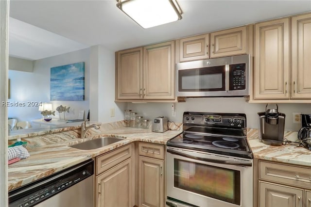 kitchen with stainless steel appliances, light stone countertops, sink, and light brown cabinets