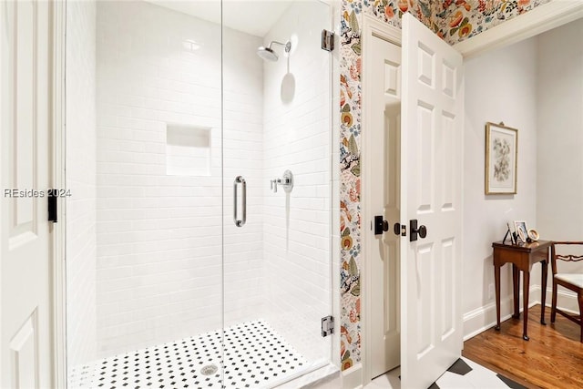 bathroom with a shower with door and hardwood / wood-style floors