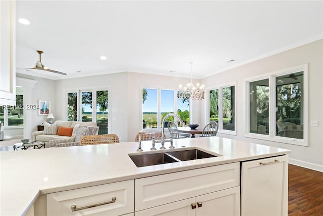 kitchen with sink, dark wood-type flooring, white cabinets, and decorative light fixtures