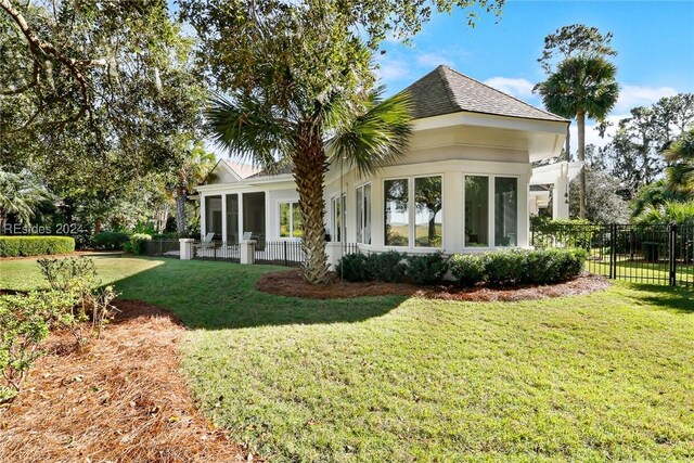 back of property with a sunroom and a lawn