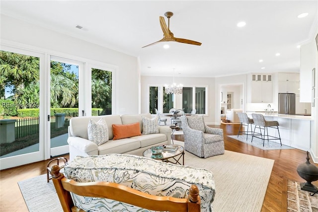 living room featuring crown molding, sink, and light hardwood / wood-style flooring